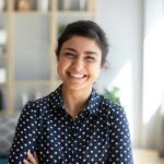 woman crossing her arms smiling in a polkadot shirt
