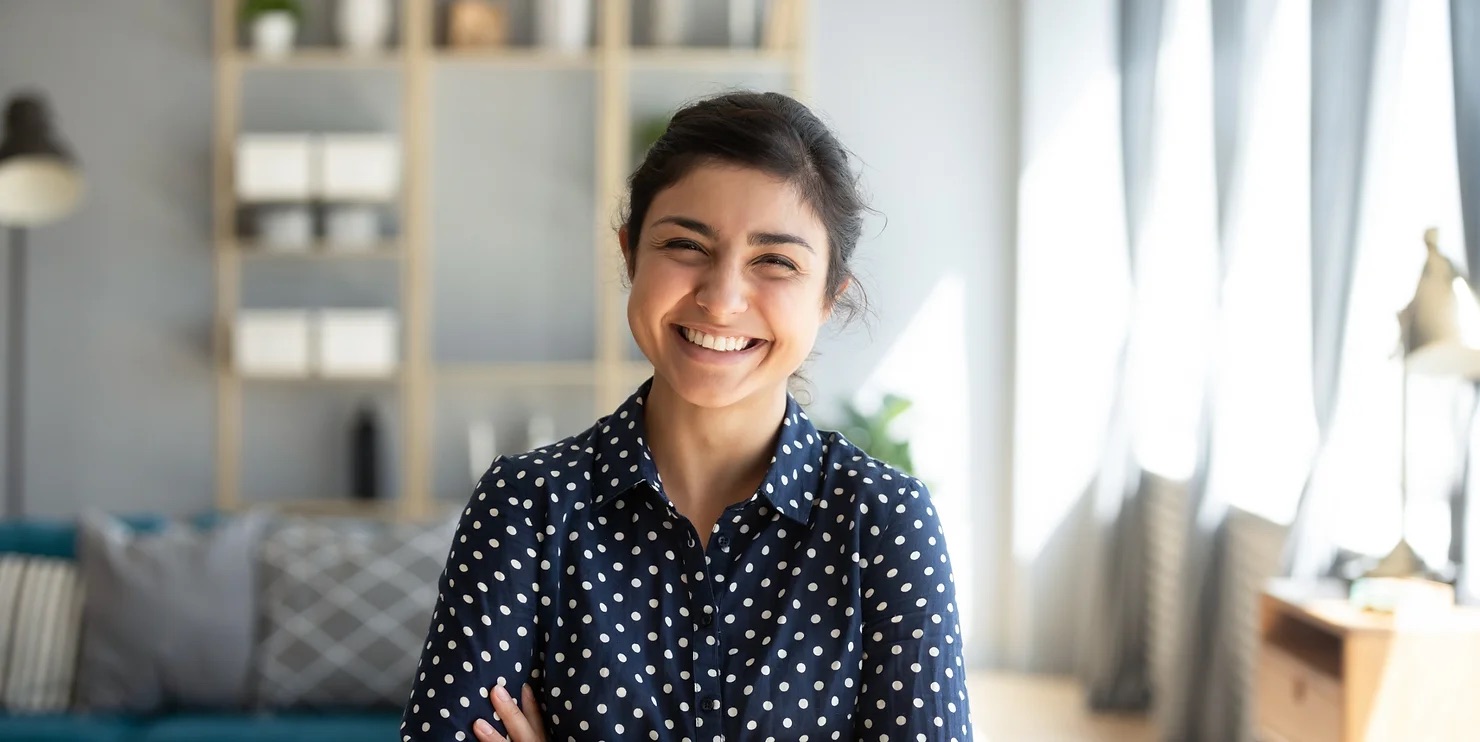 woman crossing her arms smiling in a polkadot shirt