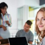 woman looking back behind her while other co-workers are collaborating