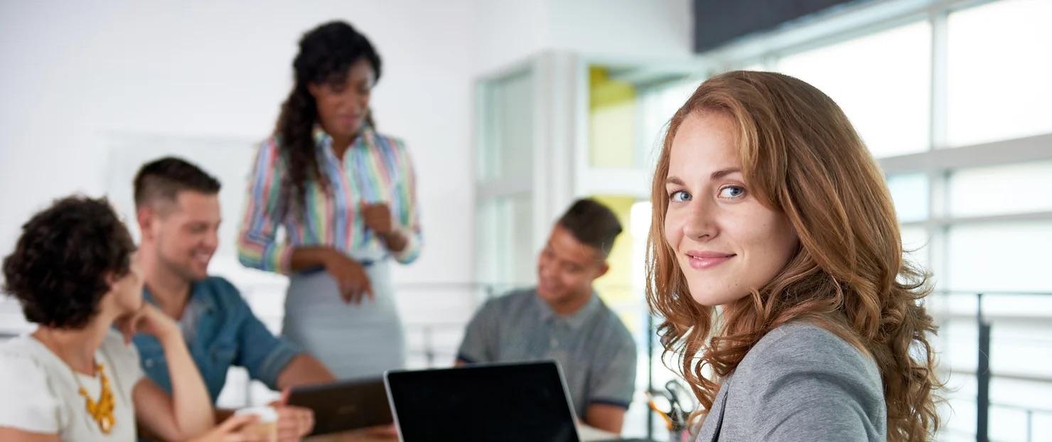 woman looking back behind her while other co-workers are collaborating